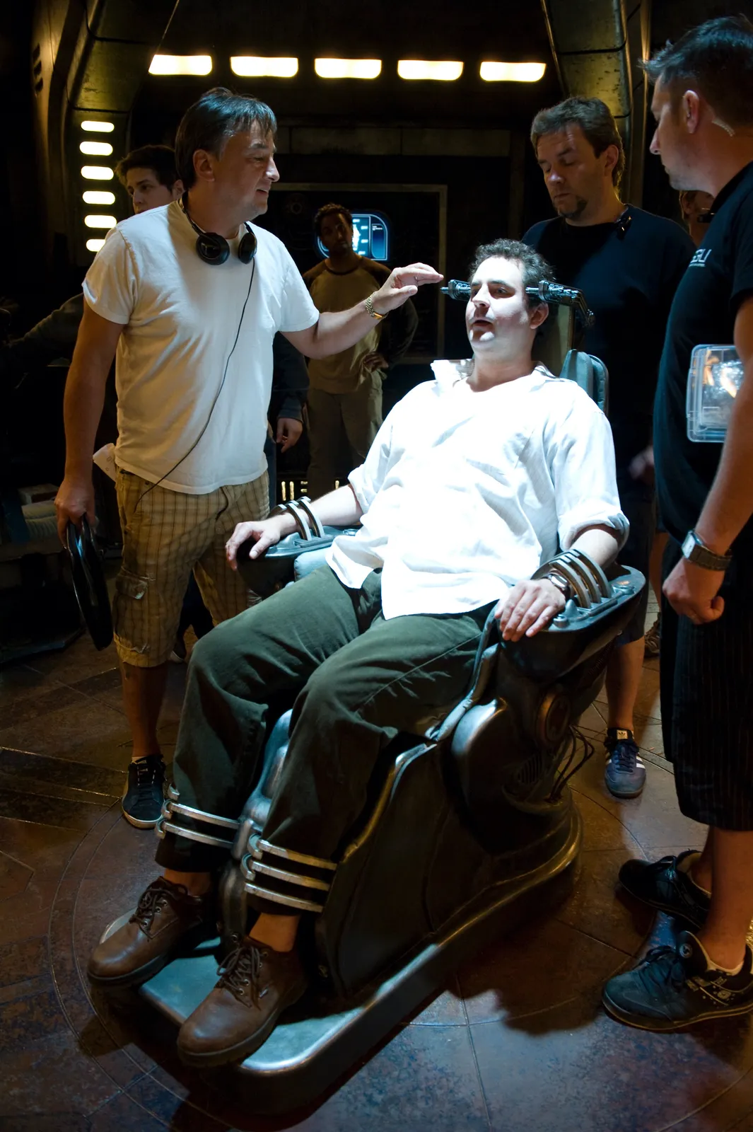 Director Will Waring makes an adjustment to actor Mark Burgess's Ancient massage chair. Behind the scenes on -…